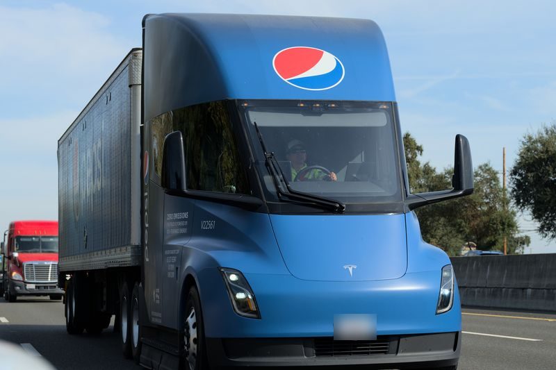 A blue Pepsi-liveried Tesla Semi truck driving on a California freeway